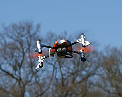 SQ1 mini quadcoper flying against spring treetops and blue sky